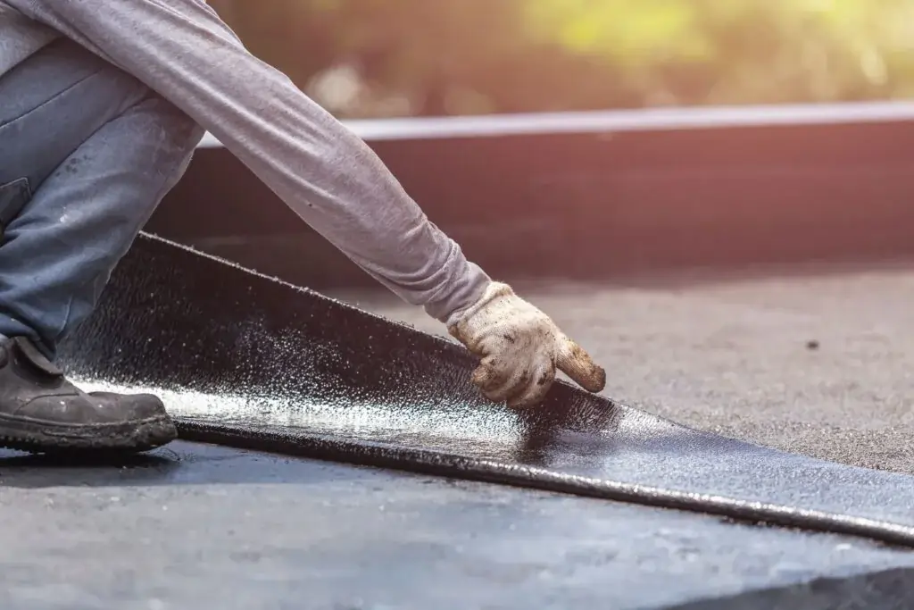 Professional roofer applying bitumen membrane during flat roofs services in Bristol