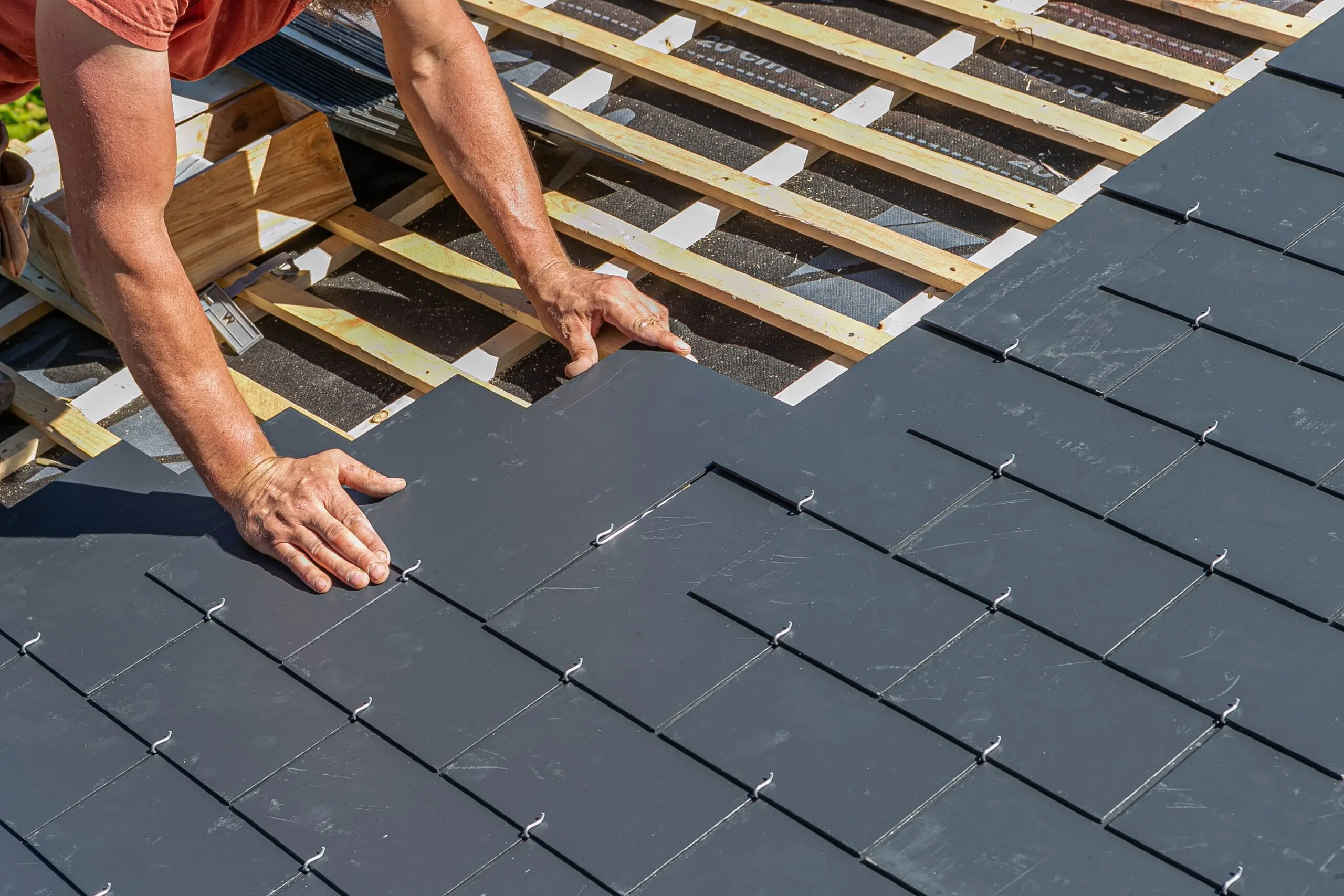 Contractor installing slate roof tiles on a residential property in Bristol with evenly aligned dark slate shingles